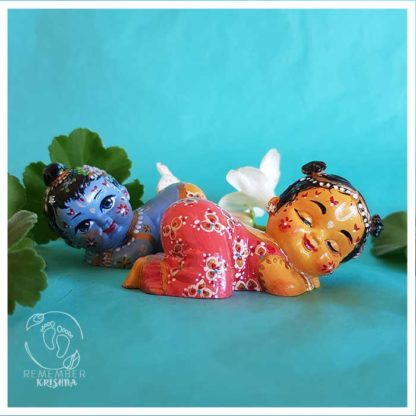 radha krishna dolls babies snuggling up and cuddling dolls radha two buns and gopi outfit krsna dhoti tilak peacock feather on a turquoise background with white jasmine flowers around them buy dolls from rememberkrishna.com