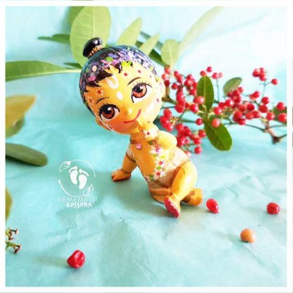 baby Nimai sitting on turquoise background with red berries and leaves and flower garland flower crown and beautiful ornaments