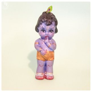 standing Krishna doll with finger in mouth peacock feather in hair and golden dhoti