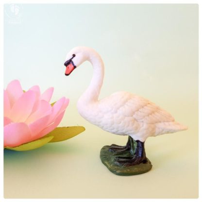 swan toy plastic doll standing and lotus flower in background on aquamarine colored cardboard for sale