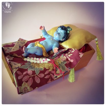 Baby Krishna statue in cradle with red satin sheets and golden pillow with tassels janmastami baby krsna figure