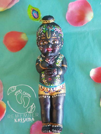 little syamasundar doll with his finger in his mouth krsna peacock feather and dhoti