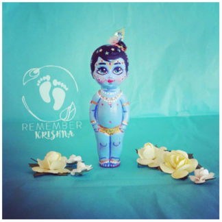 Krishna stands on blue background with yellow paper flowers is a doll for sale