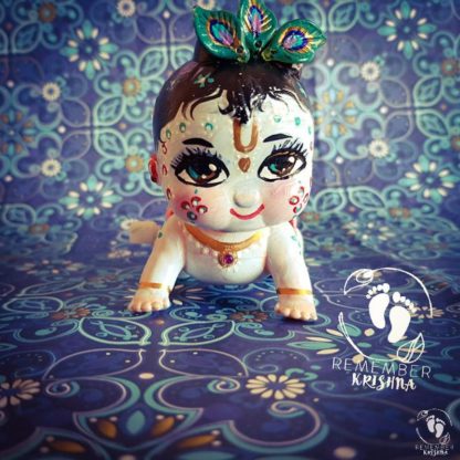 Crawling Krishna with wide eyes and peacock feathers tilak and light blue