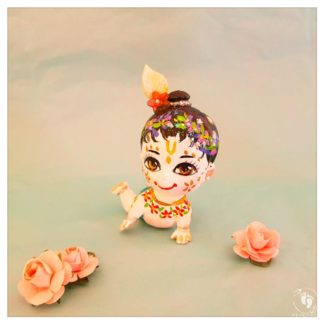 Crawling white skinned balaram doll with bun flower garlands and crawling on hands knees blue background with paper pink roses