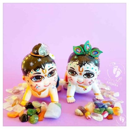 krsna and balaram chubby cute wind up toy dolls crawl along on a purple background with gems