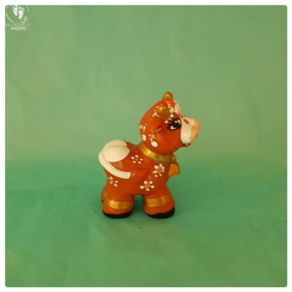 krishna cow friend toy brown cow with white patches on aqua background with traditional indian decoration and golden horns lovely long eyelashes and a cow bell