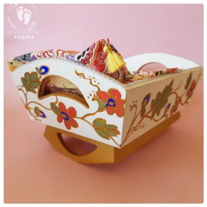 rocking cradle for Krsna dolls painted blue with daisy and blueberry folk art style and blue flowery bedding wooden cradle on pink background