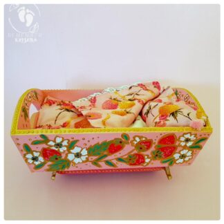 rocking cradle painted pink with strawberries gold highlights and green leaves indian folk art style on wooden cradle pink background