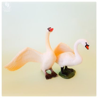 swan toy plastic doll standing and lotus flower in background on aquamarine colored cardboard for sale