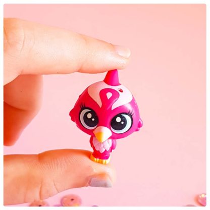 red robin toy bird friend of krishna on a pink background with purple sequins held between two kids fingers