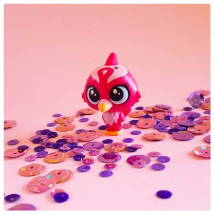 red robin toy bird friend of krishna on a pink background with purple sequins