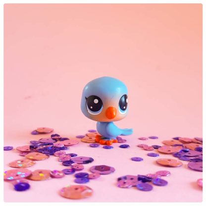 rosy little blue bird on a pink background of sequins