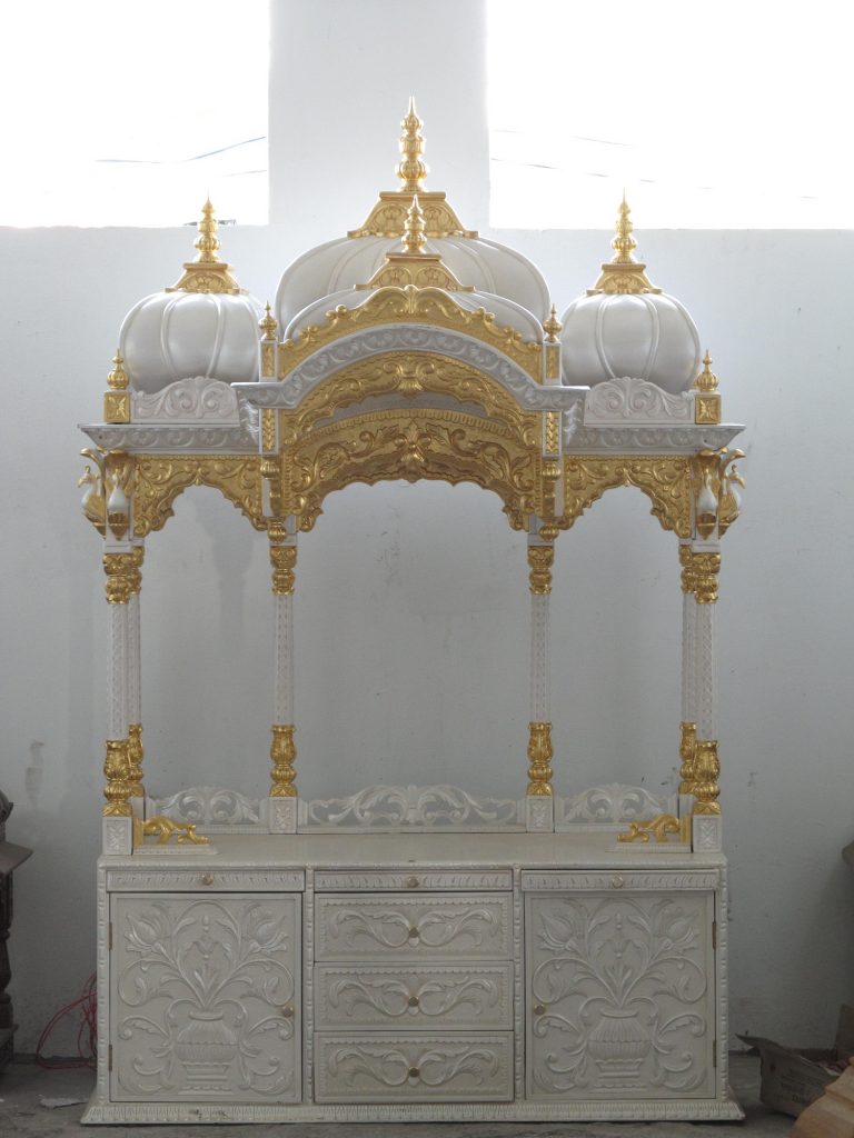 white marble carved temple with gilded gold details and ornate blown temple roof open to the room 