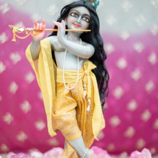 Marble krishna deity stormy blue hue against a pink spotted background wearing a luscious black deity wig hairs for murti and yellow dhoti yellow chaddar yellow sash and dupatta