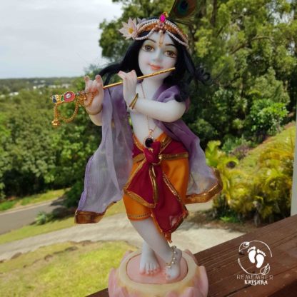 12 inch Krishna murti in white marble painted and garmented with shrinigar against natural background deity of kahna