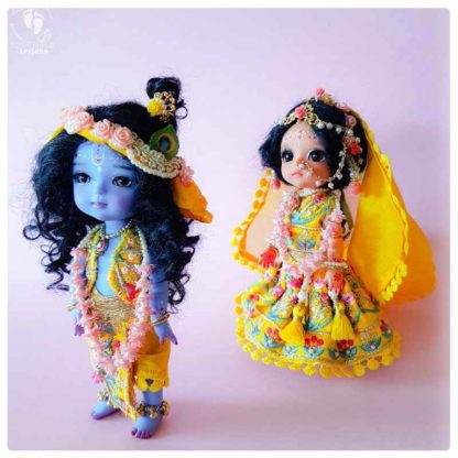 Krishna doll adorable little Krishna standing with sweet smile and levely yellow dhoti vest turban and flower garlands Sri Radhe doll dressed in matching golden garments with flower crowns and pretty decorations