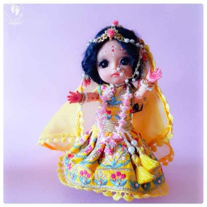 Radha rani with gorgeous yellow veil nd matching outfit embroidered with flowers photo on pink background with pearls and flowers in her hair a lengha dupatta and custom dressed doll