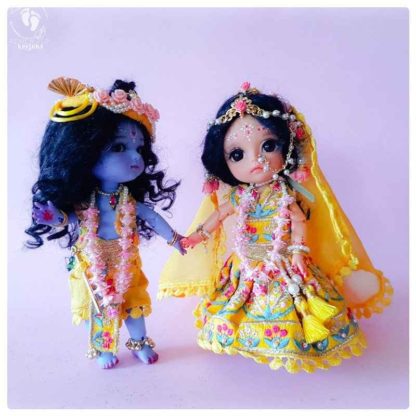 Krishna doll adorable little Krishna standing with sweet smile and levely yellow dhoti vest turban and flower garlands Sri Radhe doll dressed in matching golden garments with flower crowns and pretty decorations
