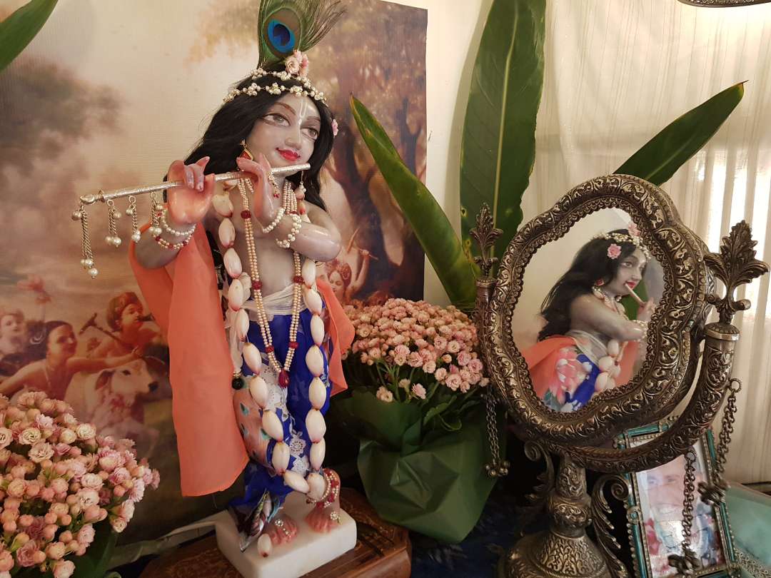 Sri Vanvihari in peacock blue peach and ginger flower lotus bud garland reflected in a silver ornate mirror