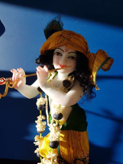 Krishna deity 12 inch on lotus base sri Hari with a garland of jasmine and berries, on a blue background wearing a yellow turban and dhoti