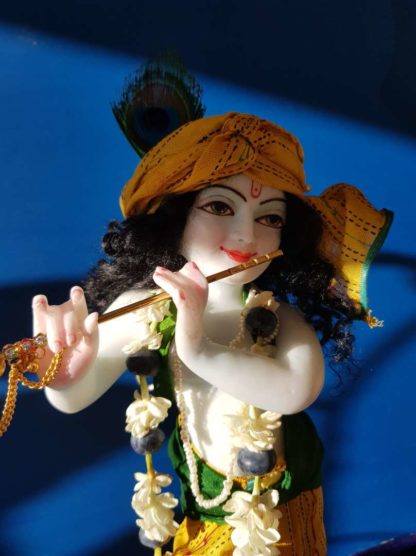 Krishna deity 12 inch on lotus base sri Hari with a garland of jasmine and berries, on a blue background wearing a yellow turban and dhoti