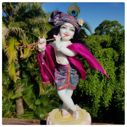 Krishna deity 12 inch on lotus base sri Hari purple outfit side view full length with purple and peacock outfit against green scenery forest background krishna murti