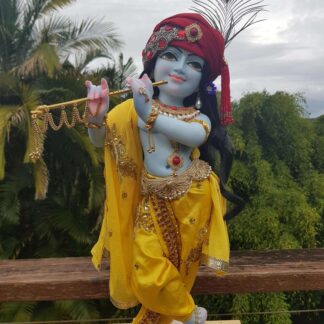 Mohana krishna deity blue deity of Krishna dressed in yellow garments with a red turban and peacock feather in his hair and playing the flute