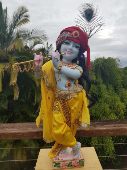 Mohana krishna deity blue deity of Krishna dressed in yellow garments with a red turban and peacock feather in his hair and playing the flute