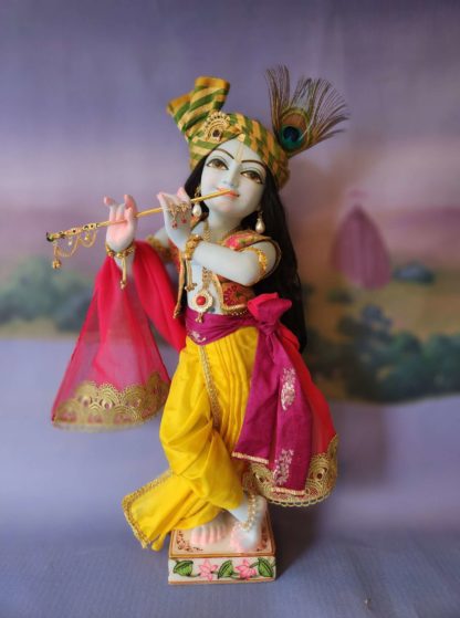 Mohana krishna deity blue deity of Krishna dressed in yellow garments with a red turban and peacock feather in his hair and playing the flute