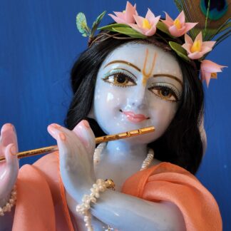 krishna deity 12 inch white marble blue colorwash hue skin dressed in red dhoti murti in three fold bending post with flute peach shawl hair and peacock feather on blue background