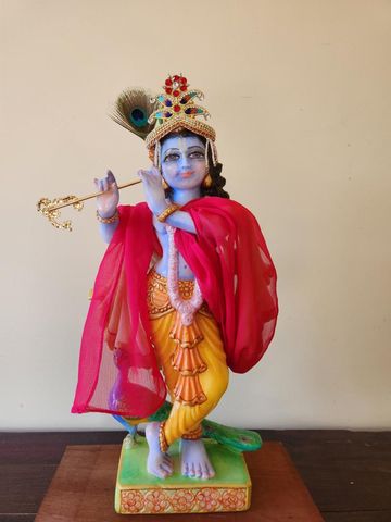 Krishna deity dressed form of lord wearing a crown shawl and peacock feather