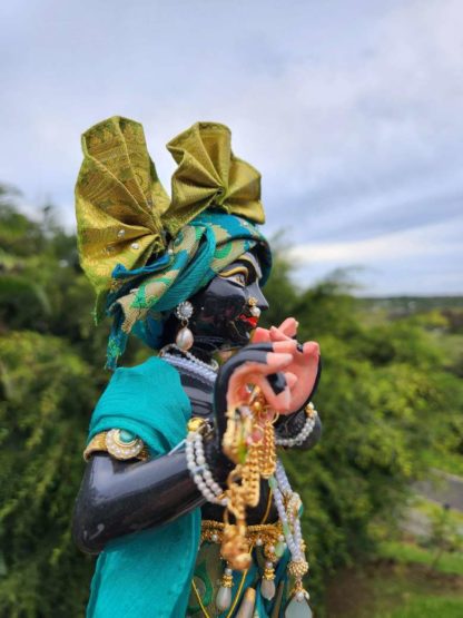 deity black marble form of lord krishna murti radha kanta wearing peacock coloured garments and holding a flute