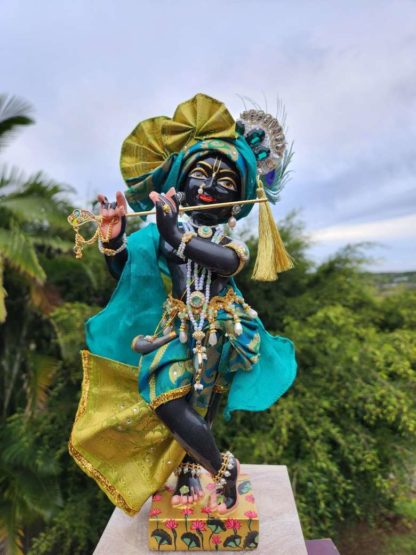 deity black marble form of lord krishna murti radha kanta wearing peacock coloured garments and holding a flute