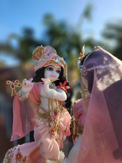 Full view of Krishna murti standing in sun playing flute