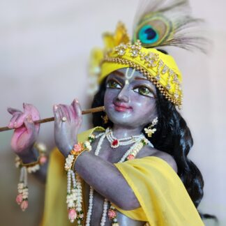 Deity of Krishna 18inch in marble painted with dark colors standing deity in three fold bend playing flute and wearing a yellow dhoti and choli with pagri and gorgeous jewelery