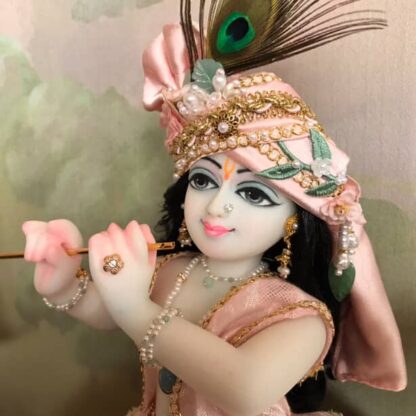 Quality white marble krishna deity hand carved Kamal Nayana weearing soft pink outfit with delicate pink hands in a pink turban and a peacock feather with delicate pearl and gold jewelery 12inch tall deity of Krishna shown holding flute