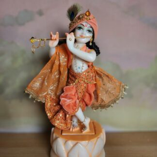 BalaGopal deity 15inch tall white marble deity of Krishna on a white lotus base pictured in a apricot and peach dhoti shawl and luxurious turban the deity is shown in the tribhanga folding form of krishna playing the flute