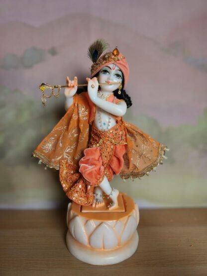 BalaGopal deity 15inch tall white marble deity of Krishna on a white lotus base pictured in a apricot and peach dhoti shawl and luxurious turban the deity is shown in the tribhanga folding form of krishna playing the flute