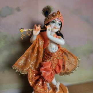 BalaGopal deity Quality white marble krishna deity hand carved Kamal Nayana weearing soft pink outfit with delicate pink hands in a pink turban and a peacock feather with delicate pearl and gold jewelery 12inch tall deity of Krishna shown holding flute. deity pictured in slight side profile focus on face and peacock feather with apricot and peach gorgeous dhoti