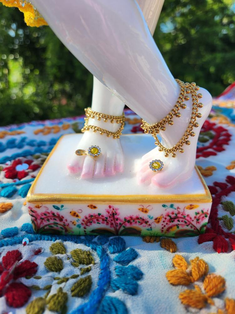 marble deity of krishna lotus feet on base with tulasi manjari printed decoration and golden anklets