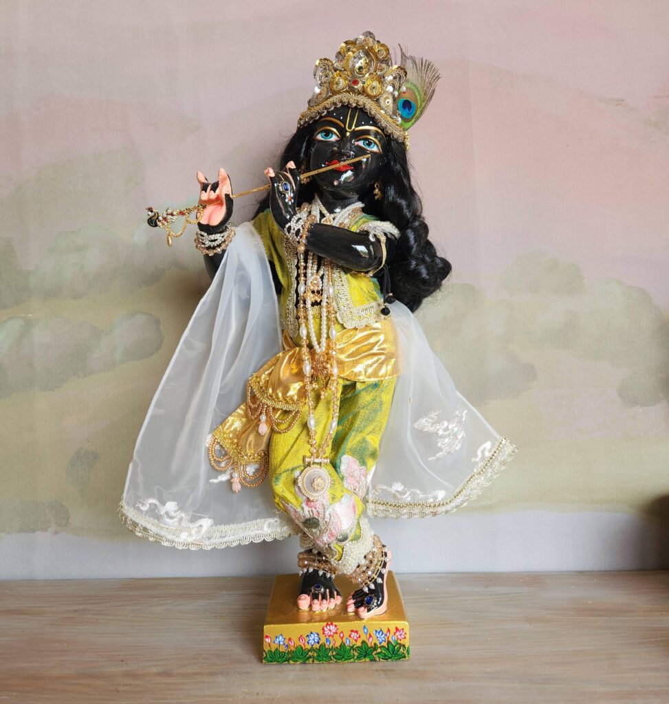 Krishna deity wearing green silk outfit, golden sash and white shawl decorated with clouds