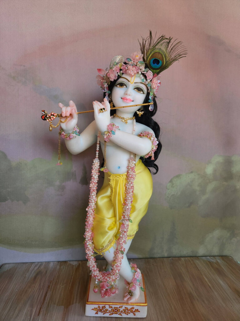 Krishna deity wearing flowery jewellery crown in pink