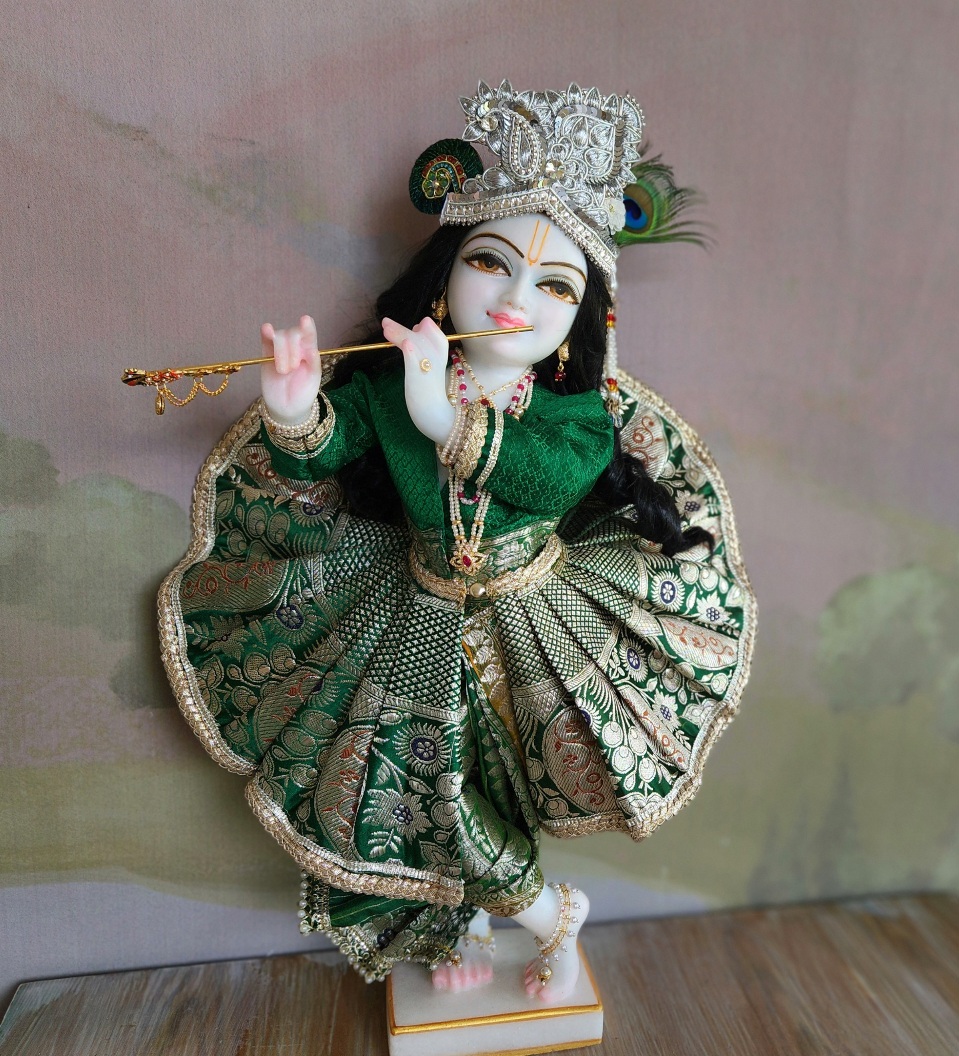 Unique white Marble Krishna deity wearing a green outfit of dhoti full flared skirt and long jacket with pearl jewellery and a silver crown with a natural peacock feather
