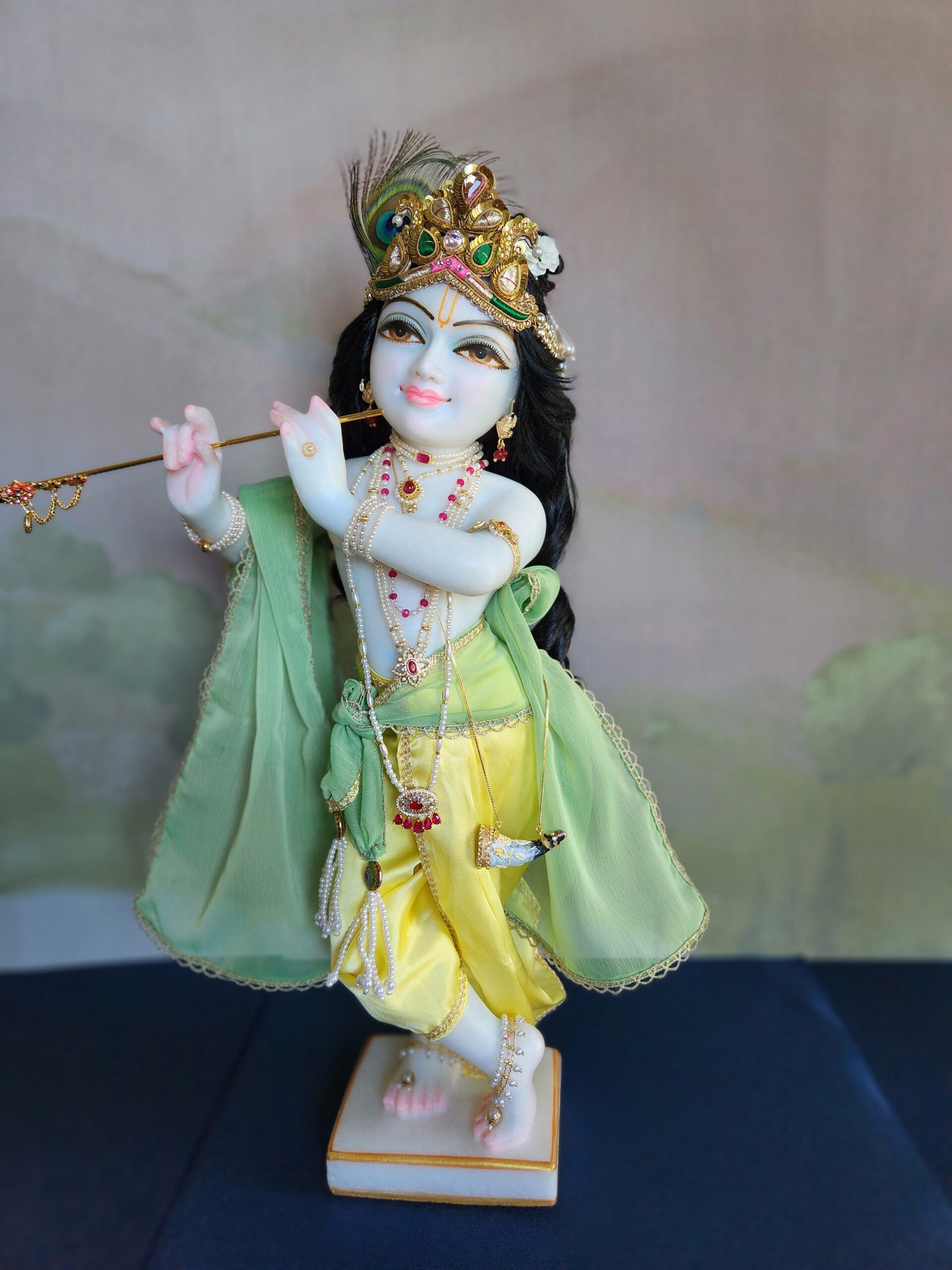 yellow and green outift krishna deity in carved white marble and crown, with a buffalo horn