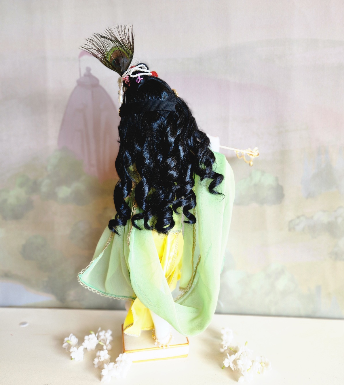 marble deity of krishna painted a soft delicate blue hue, back view with soft black curl wig