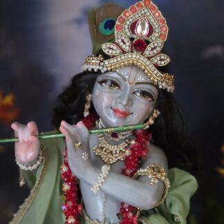 Gorgeous hand carved unique deity of Krishna in marble with a delicate hand painted finish, gentle storm cloud blue colorwash. delicate tilak markings and luminous eyes. Krishna deity, Chitta Chora, fully dressed playing flute pictured against a dark backdrop
