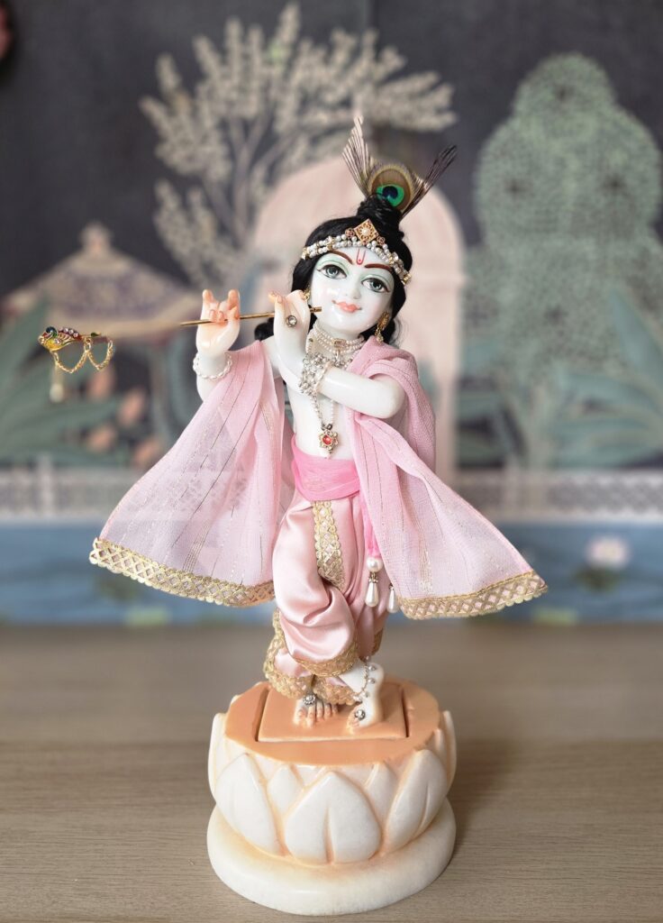 balgopal deity of krishna carved in white marble with a lotus base. dressed in delicate pink shringar