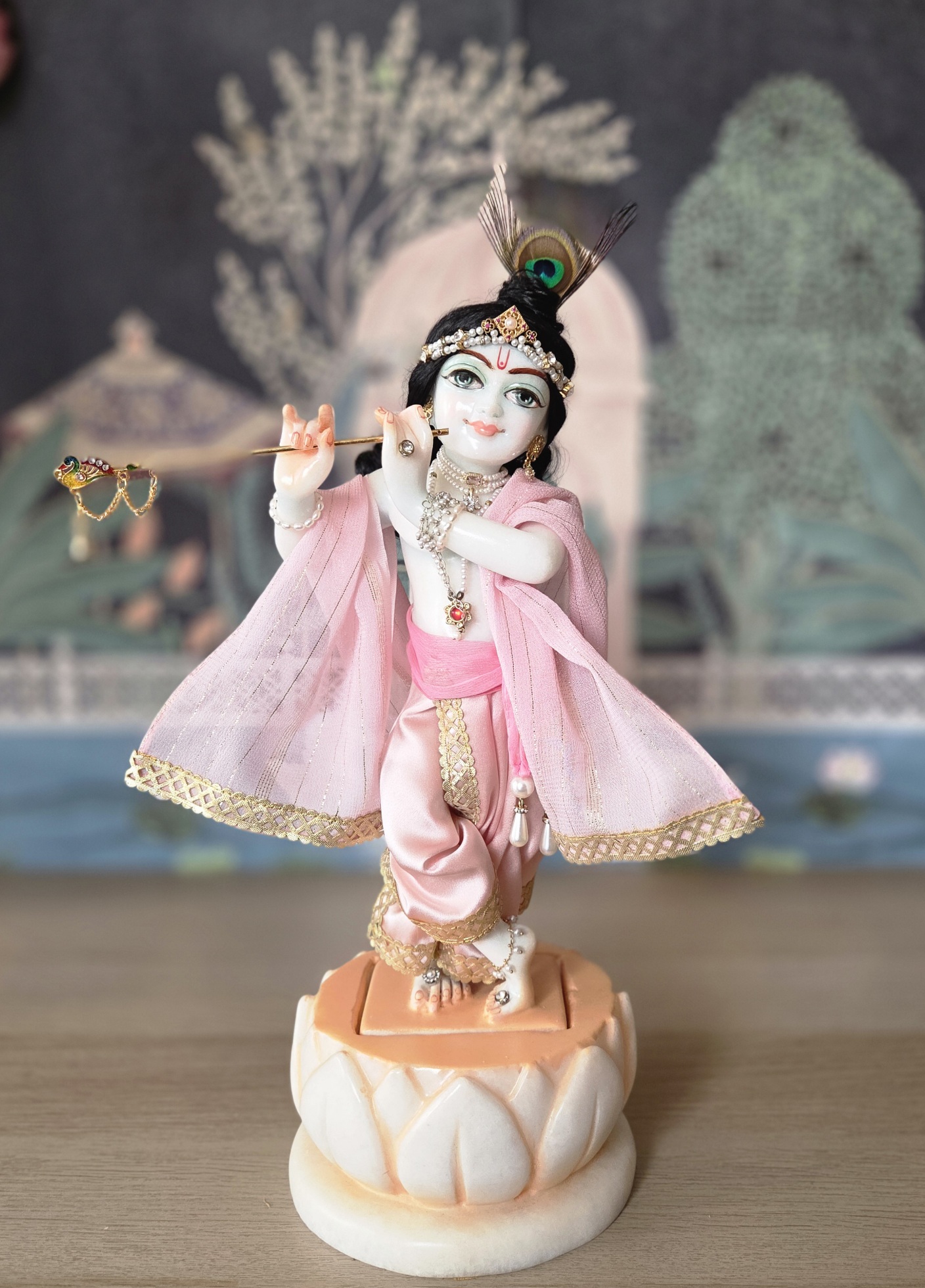 balgopal deity of krishna carved in white marble with a lotus base. dressed in delicate pink shringar