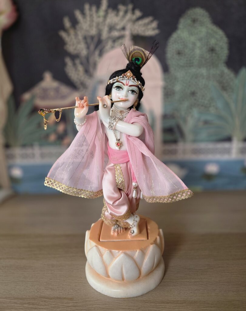 balgopal deity of krishna carved in white marble with a lotus base. dressed in delicate pink shringar